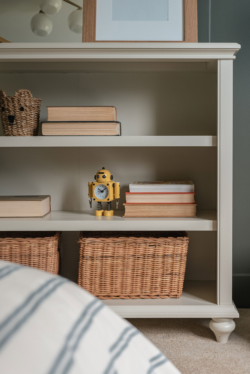 A bookshelf styled with baskets, books, and a yellow toy robot.