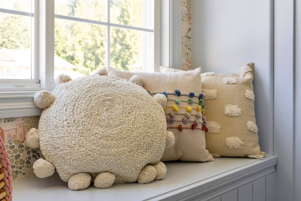Three different throw pillows on a bench in front of a window. Three different throw pillows on a bench in front of a window.