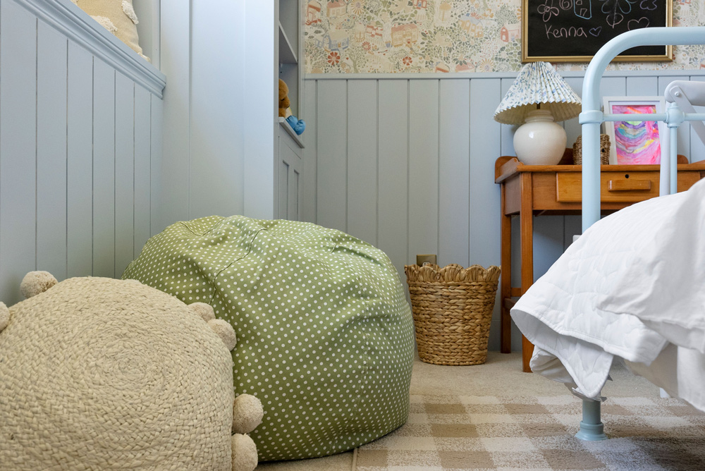 Ground-level shot of a green bean bag chair, and cream decorative pillow next to a bed. Ground-level shot of a green bean bag chair, and cream decorative pillow next to a bed.