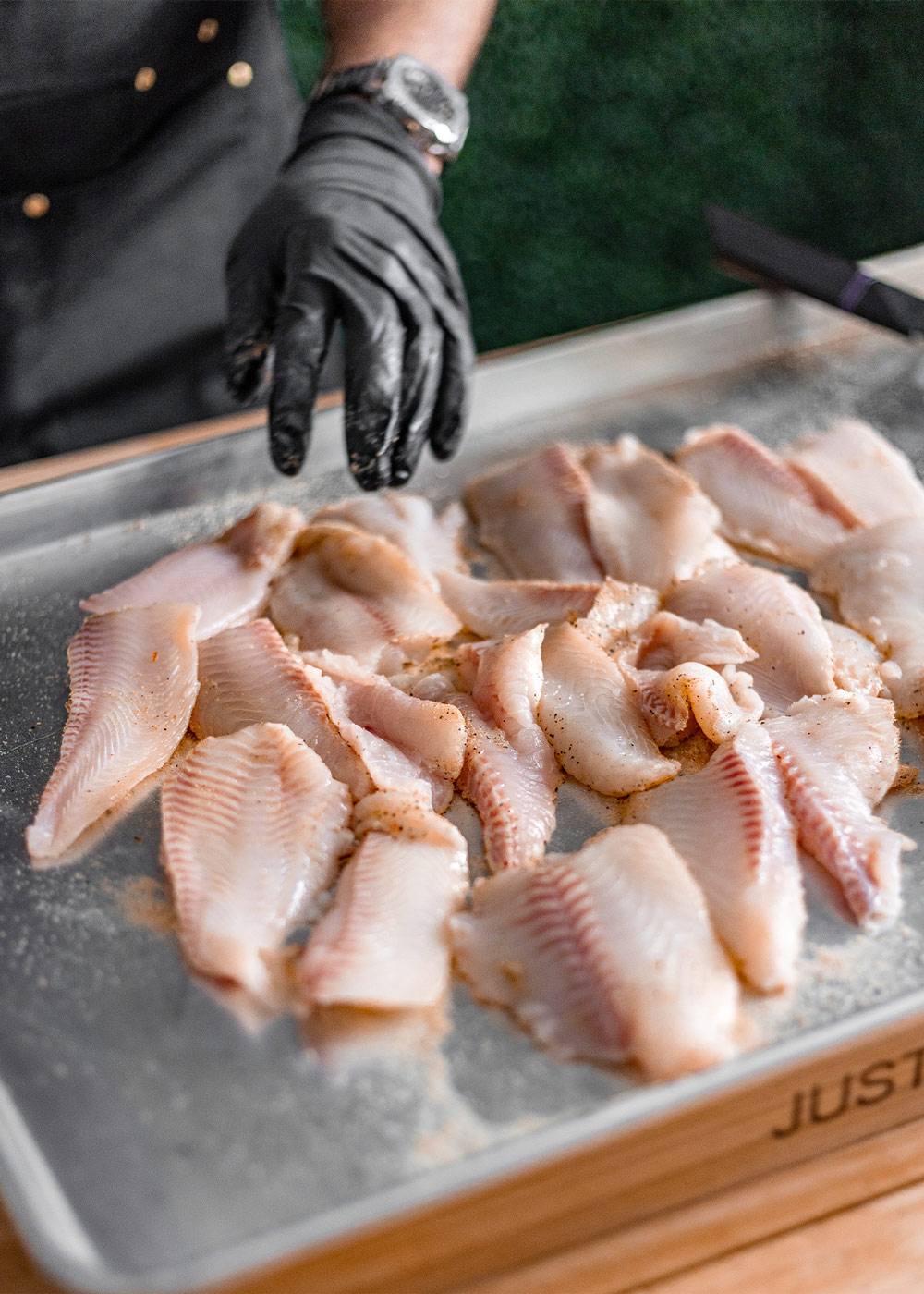 Chef preparing catfish fillets on sheet pan. Chef preparing catfish fillets on sheet pan.