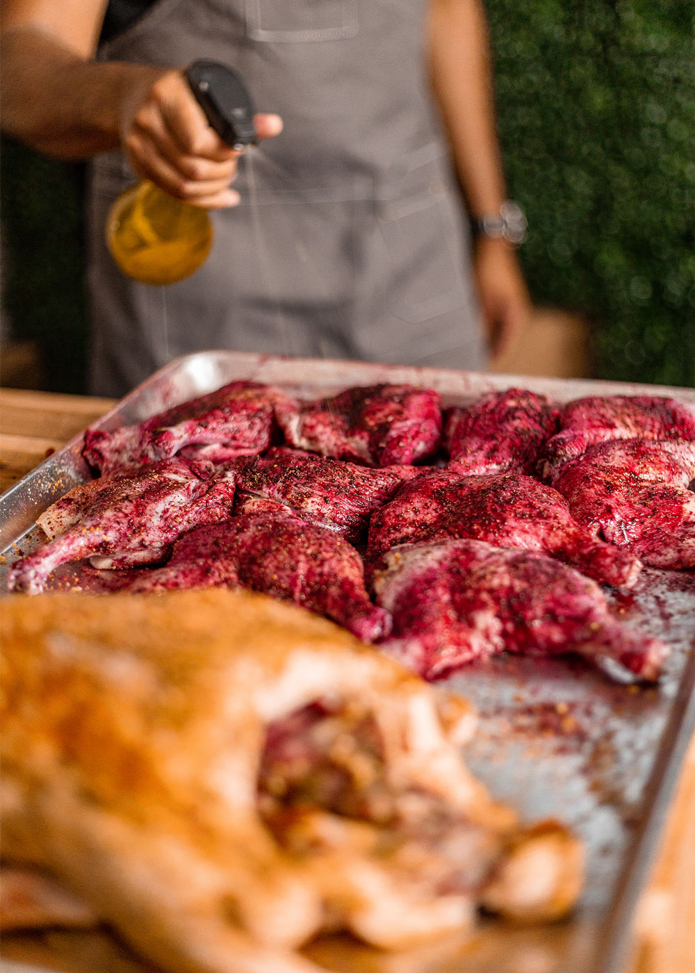 Chef applying oil to seasoned duck legs. Chef applying oil to seasoned duck legs.