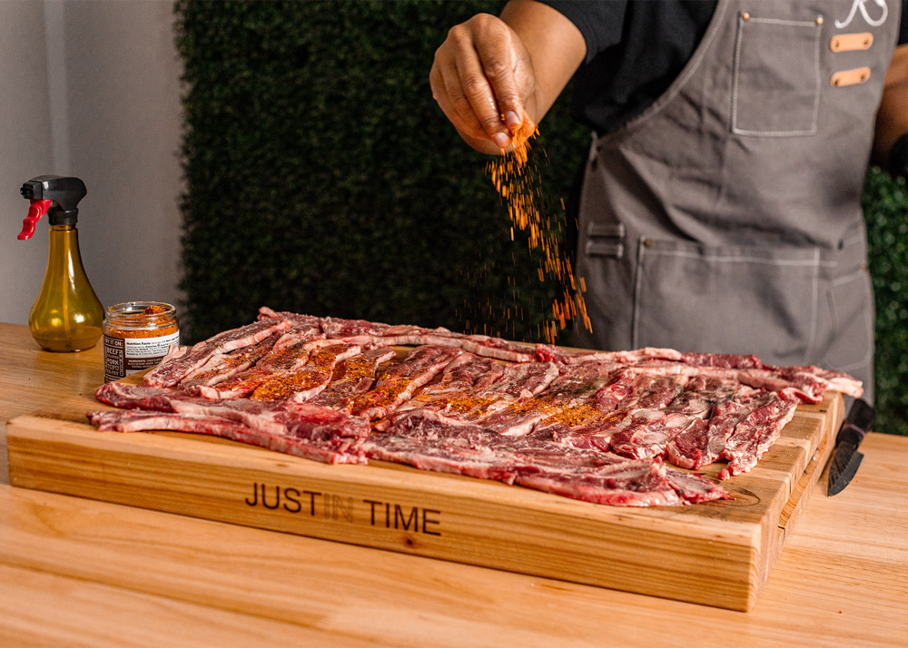 Chef seasoning riblets on cutting board. Chef seasoning riblets on cutting board.