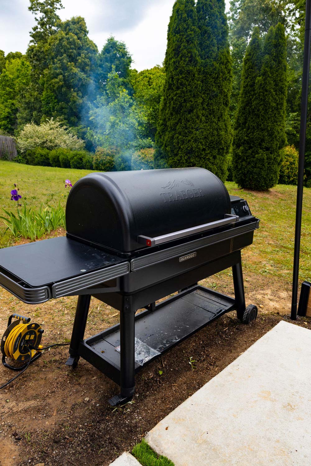 Traeger Grill in a backyard with smoke coming from the back.