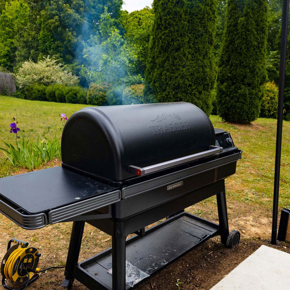Traeger Grill in a backyard with smoke coming from the back. 