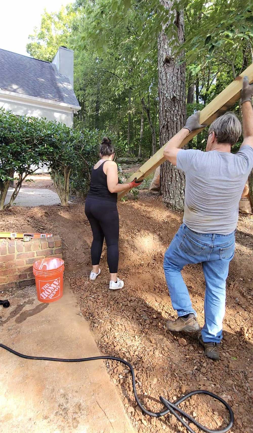A woman and a man holding a post to put into the ground.