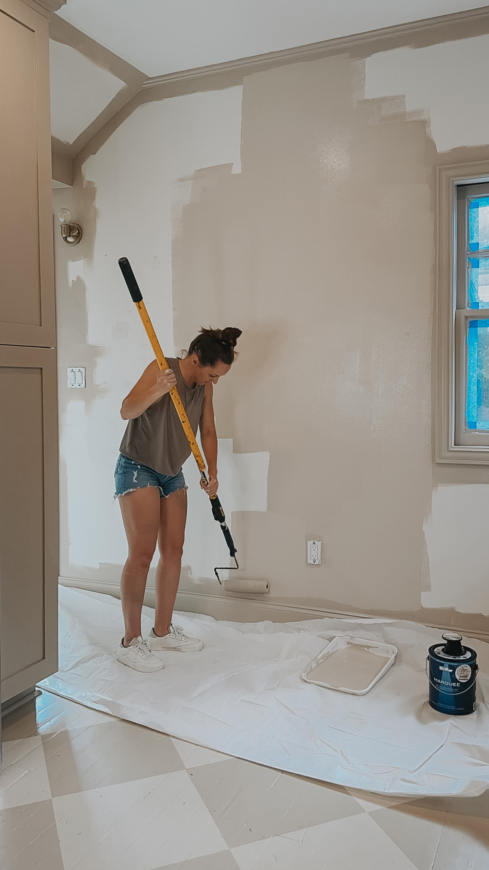 A person using a roller brush to paint a wall.