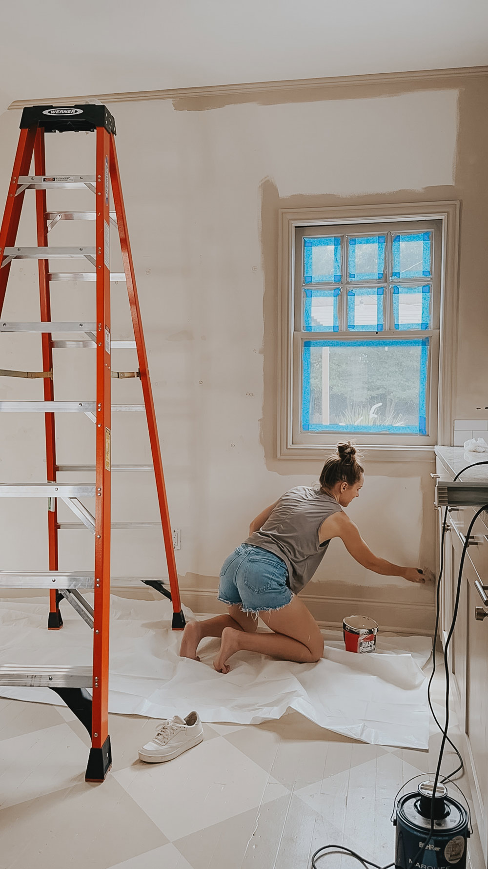 A person on the floor painting a wall next to a ladder.