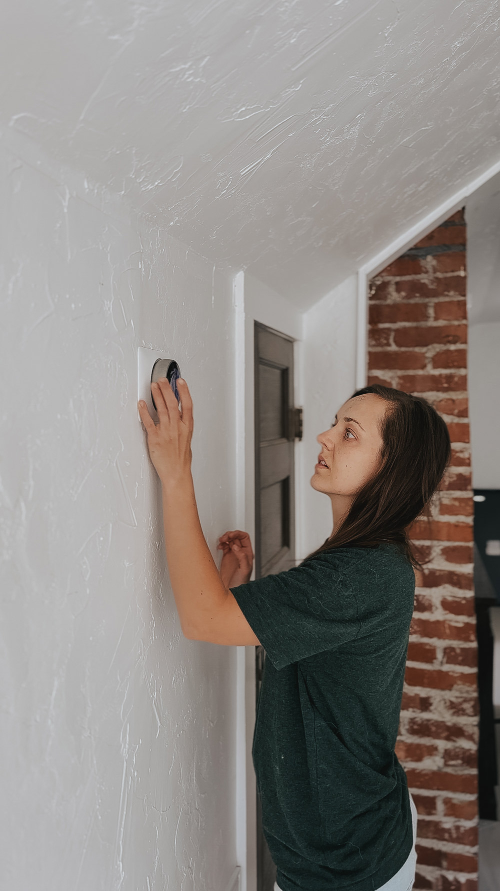 A person adding a thermostat to the wall.