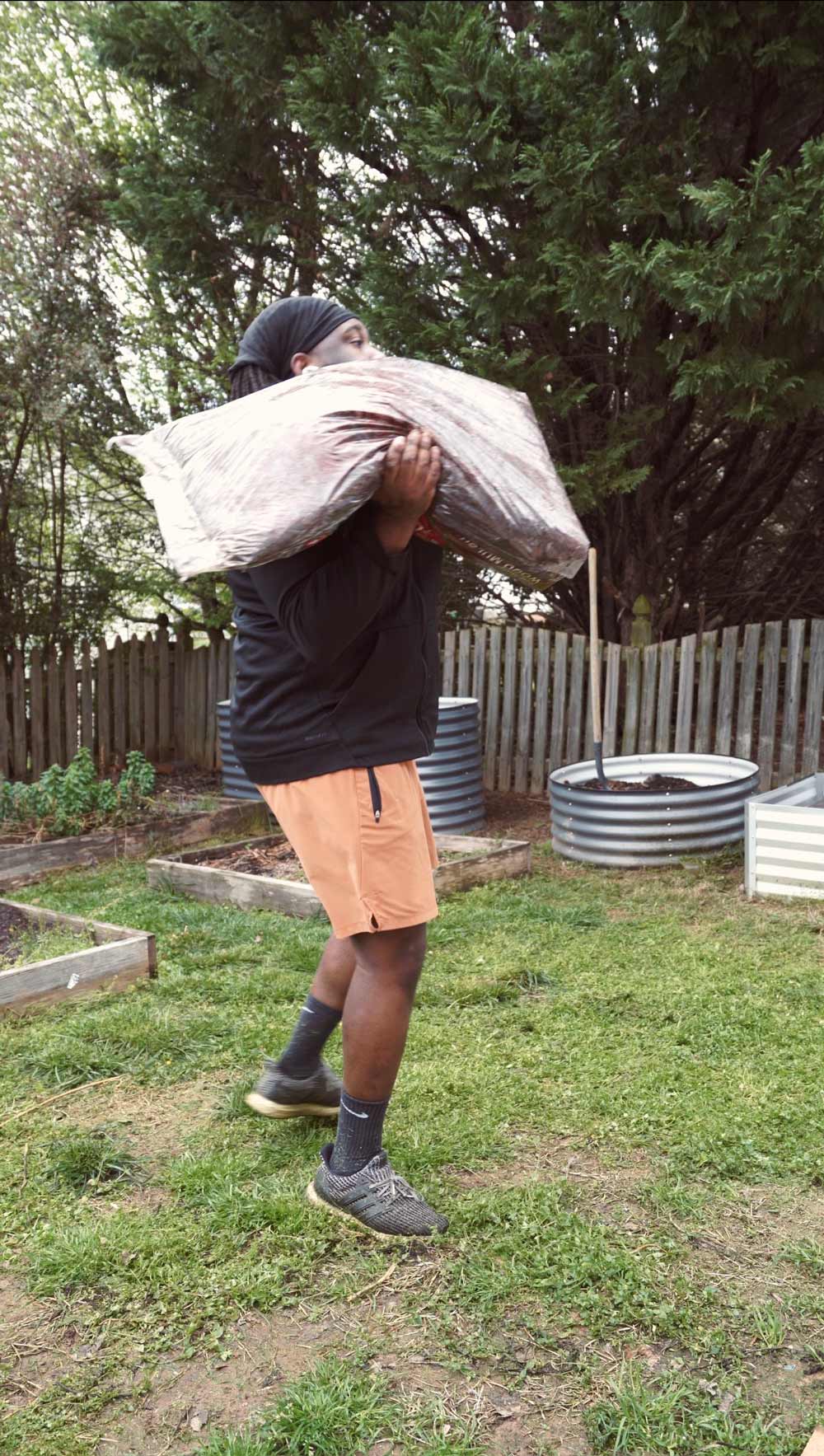 A man carrying a bag of mulch.