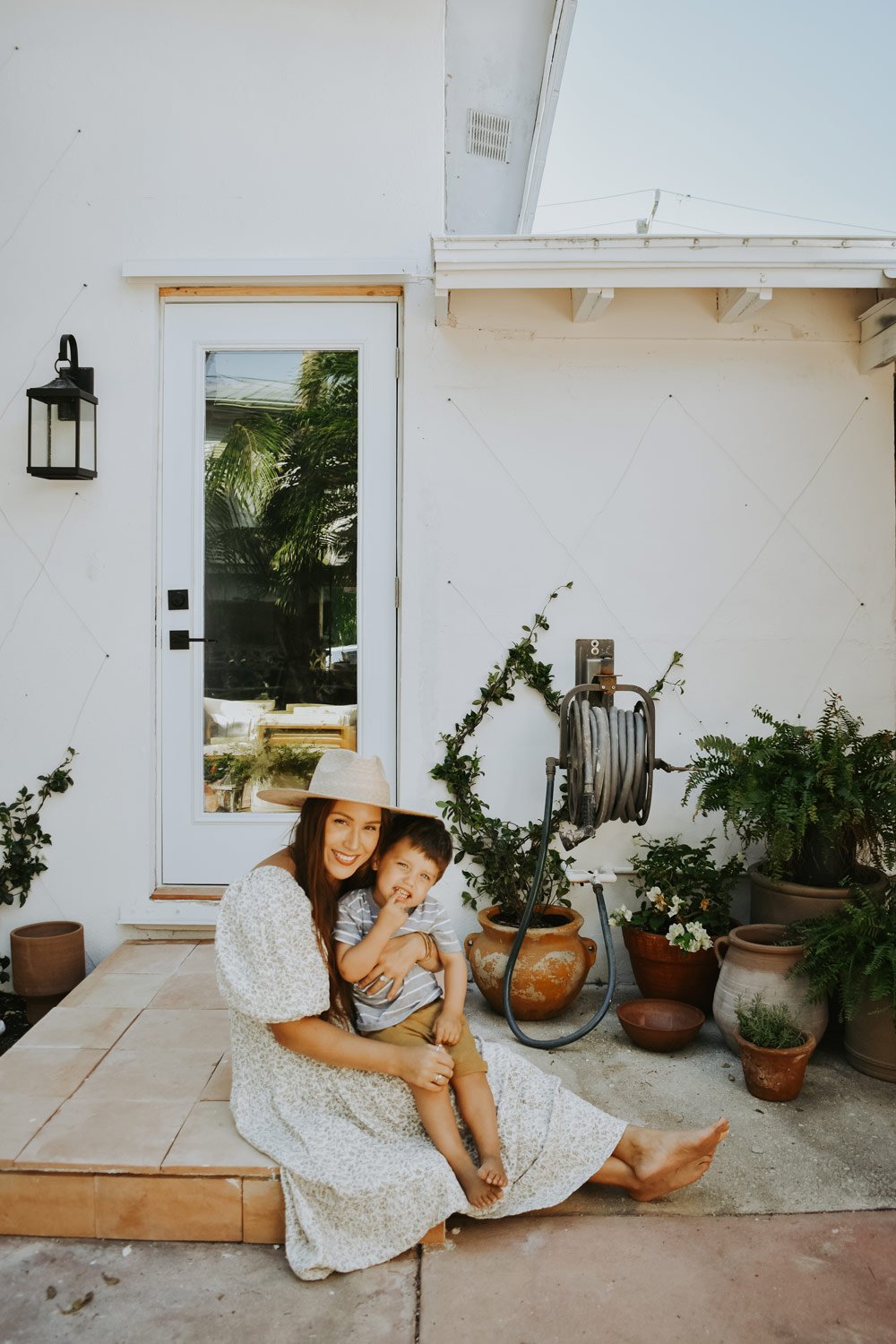 A woman holding a child while sitting on a doorway step. A woman holding a child while sitting on a doorway step.