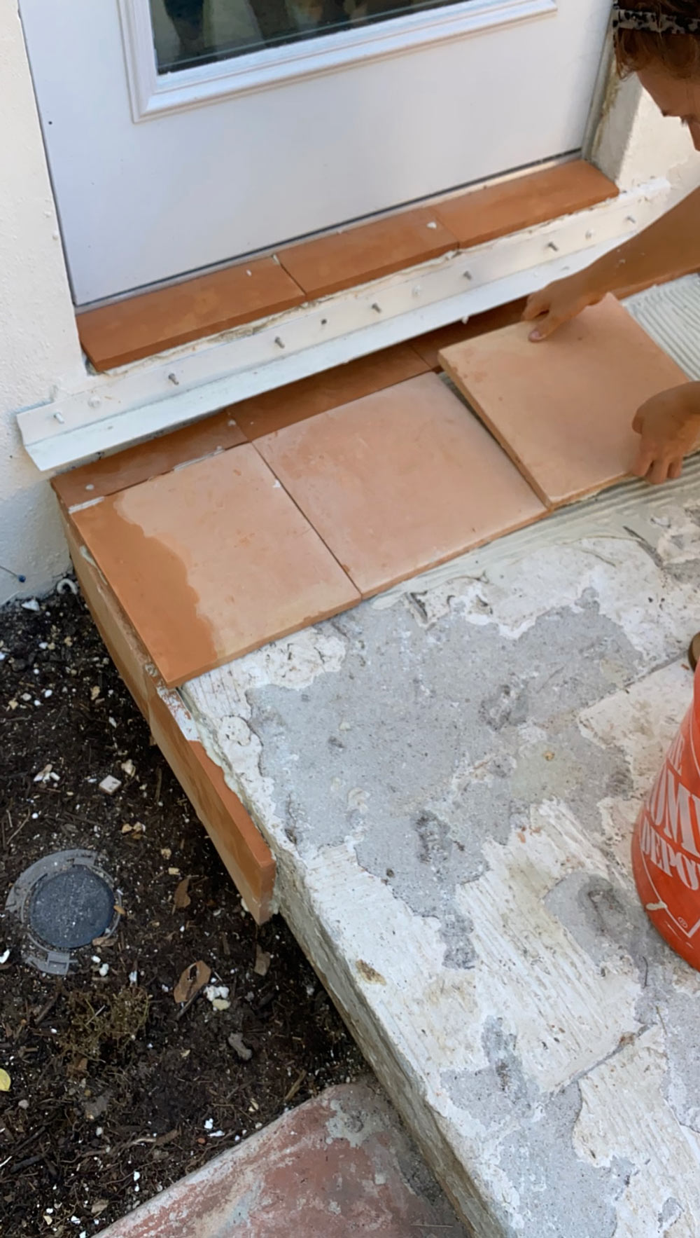 A man laying terracotta tile near a doorway. A man laying terracotta tile near a doorway.