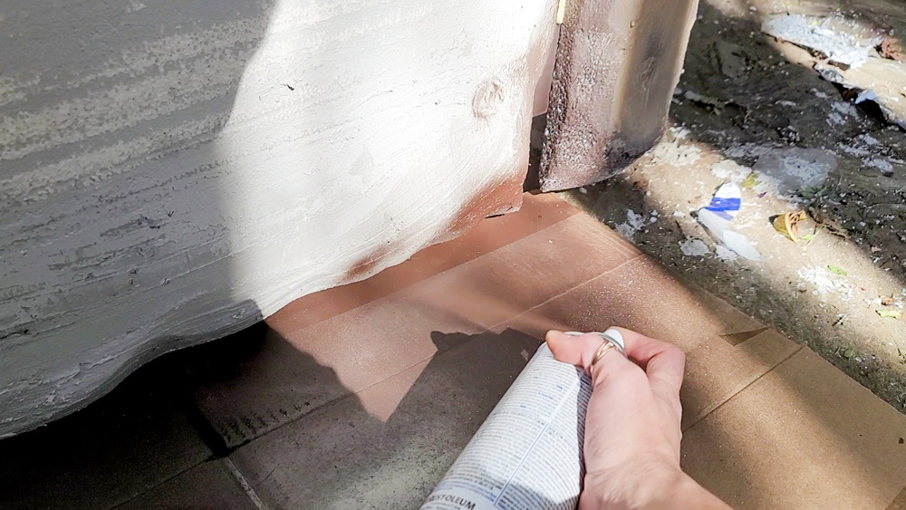 A hand applying white spray paint to a surface.