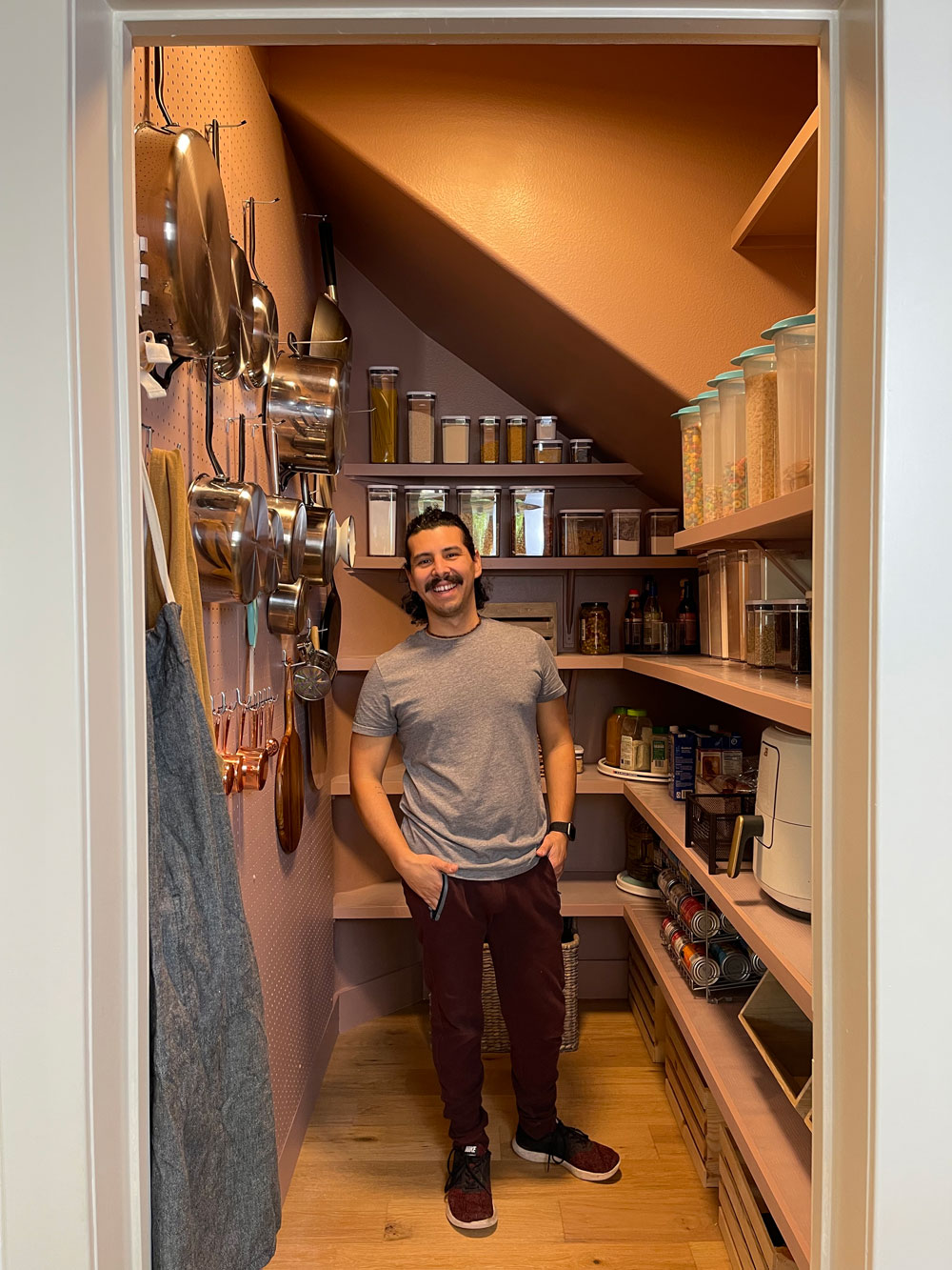 A person standing in the completely filled pantry. 