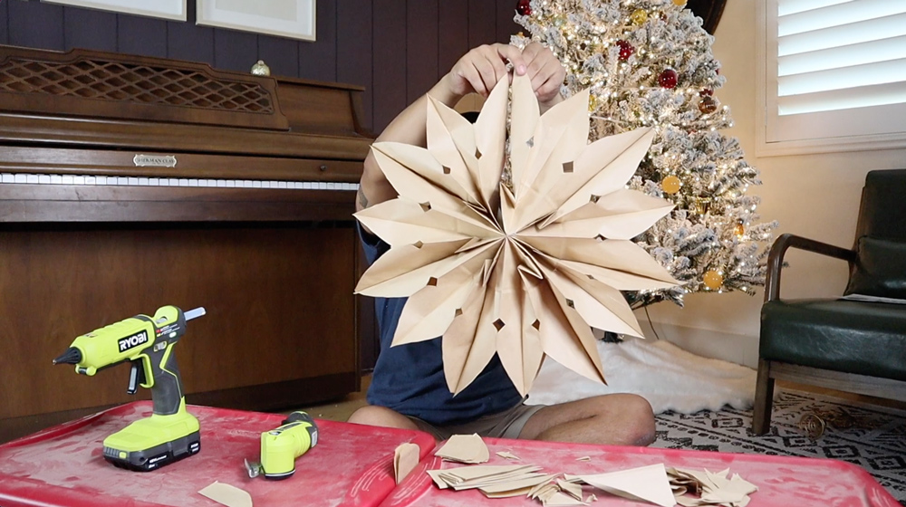 A man holding up a completed DIY paper bag snowflake. A man holding up a completed DIY paper bag snowflake.