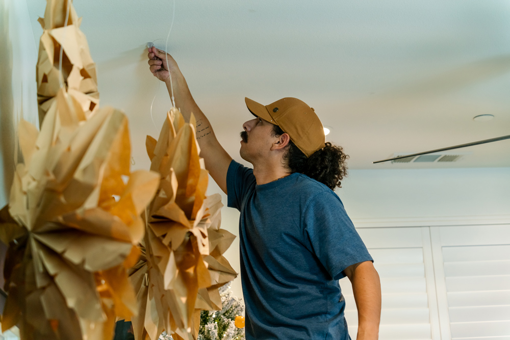 A man hanging DIY snowflakes on the ceiling. A man hanging DIY snowflakes on the ceiling.