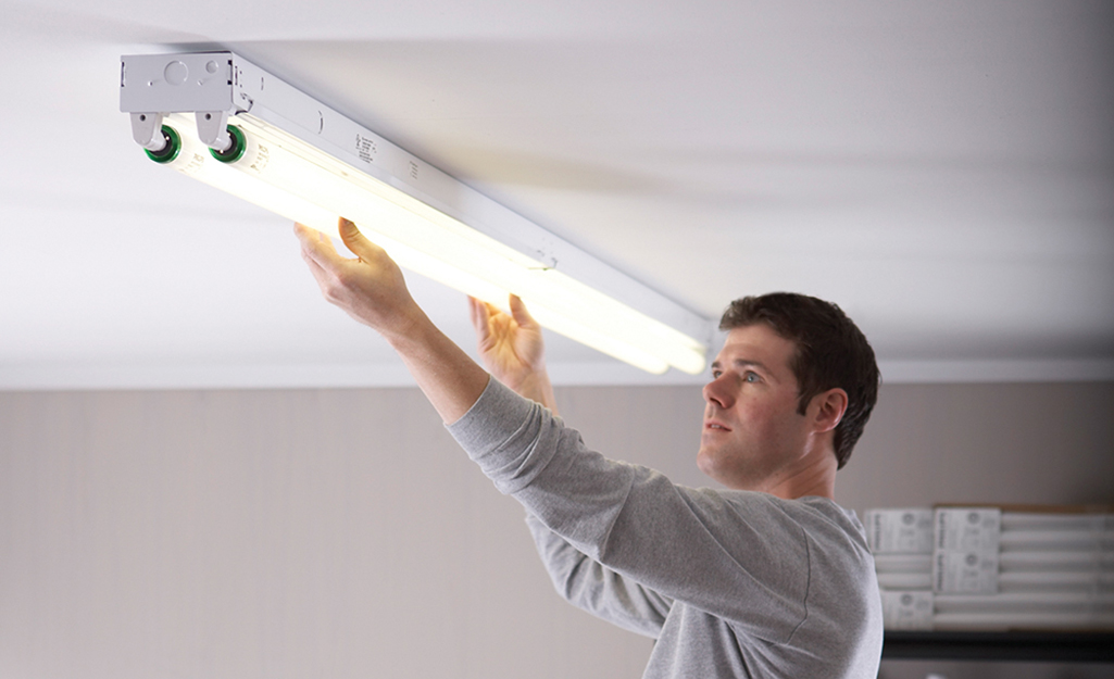 A person replaces a fluorescent light tube. 