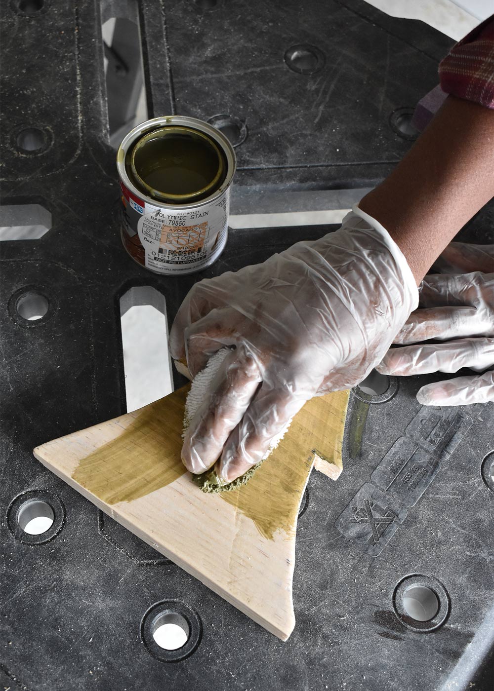 Person applying stain to wooden Christmas tree. 