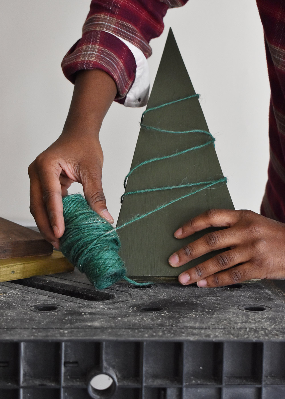 Person wrapping garden twine around wooden Christmas tree. Person wrapping garden twine around wooden Christmas tree.