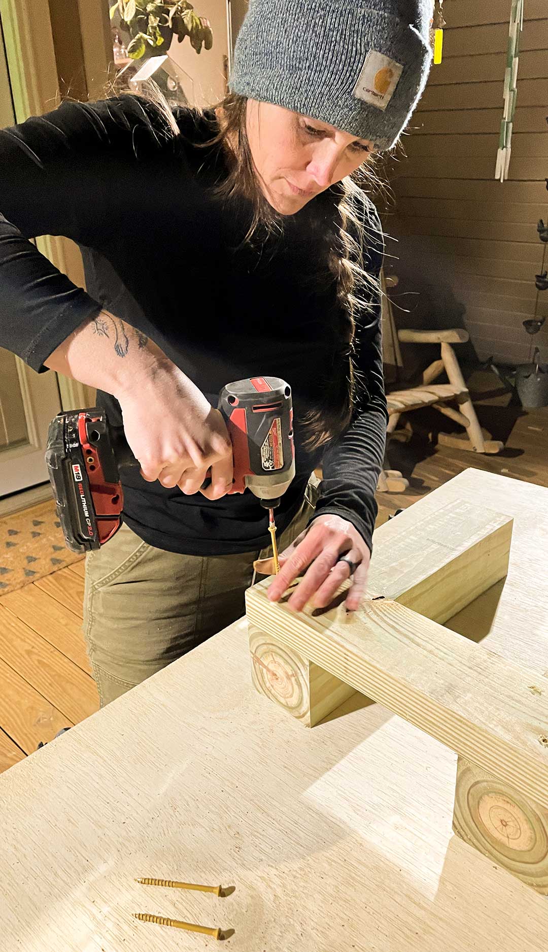 A woman drilling through two pieces of wood.