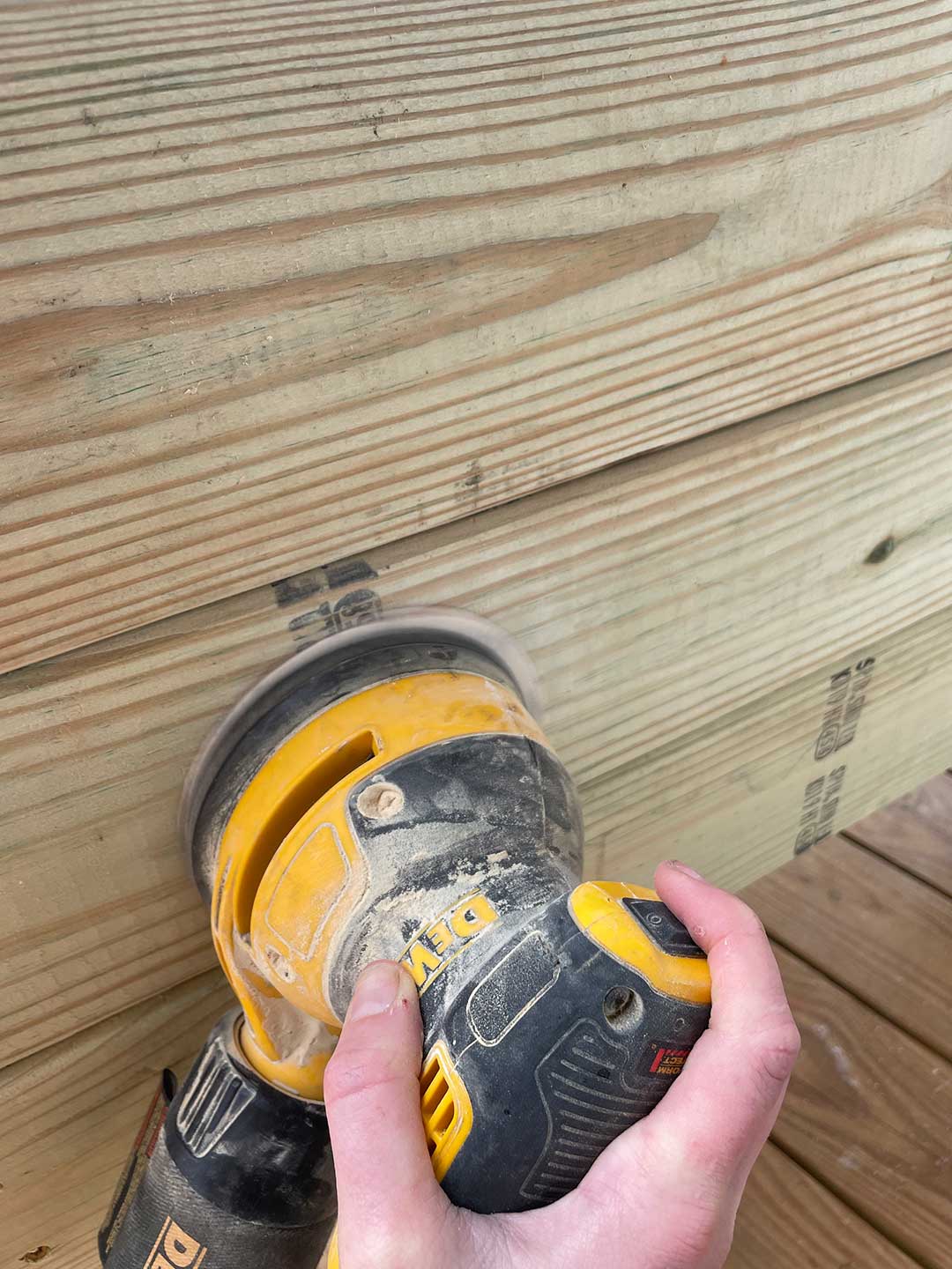 A person using a sander over wood.