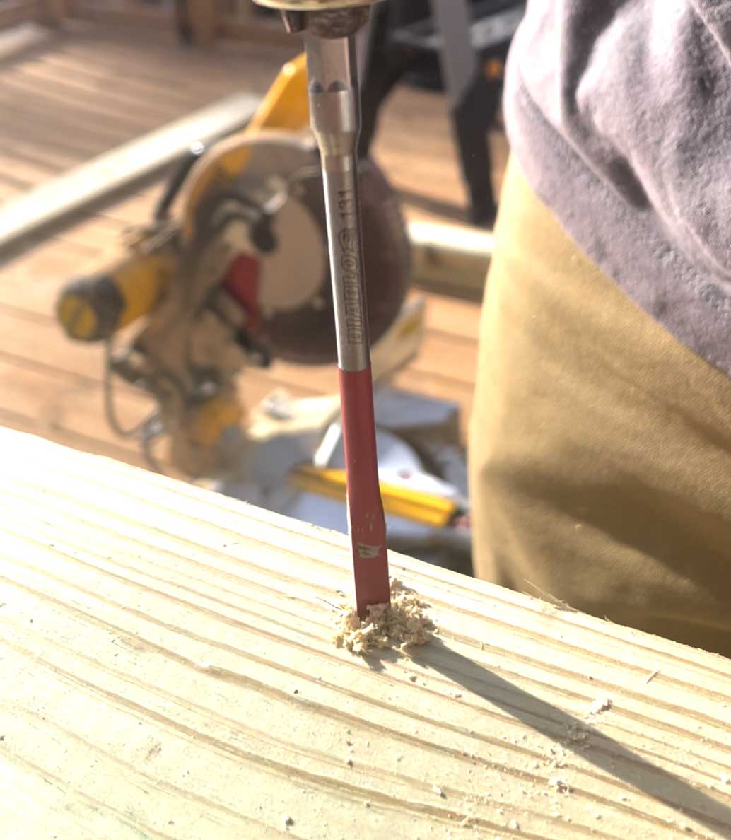 A person drilling a hole into wood.