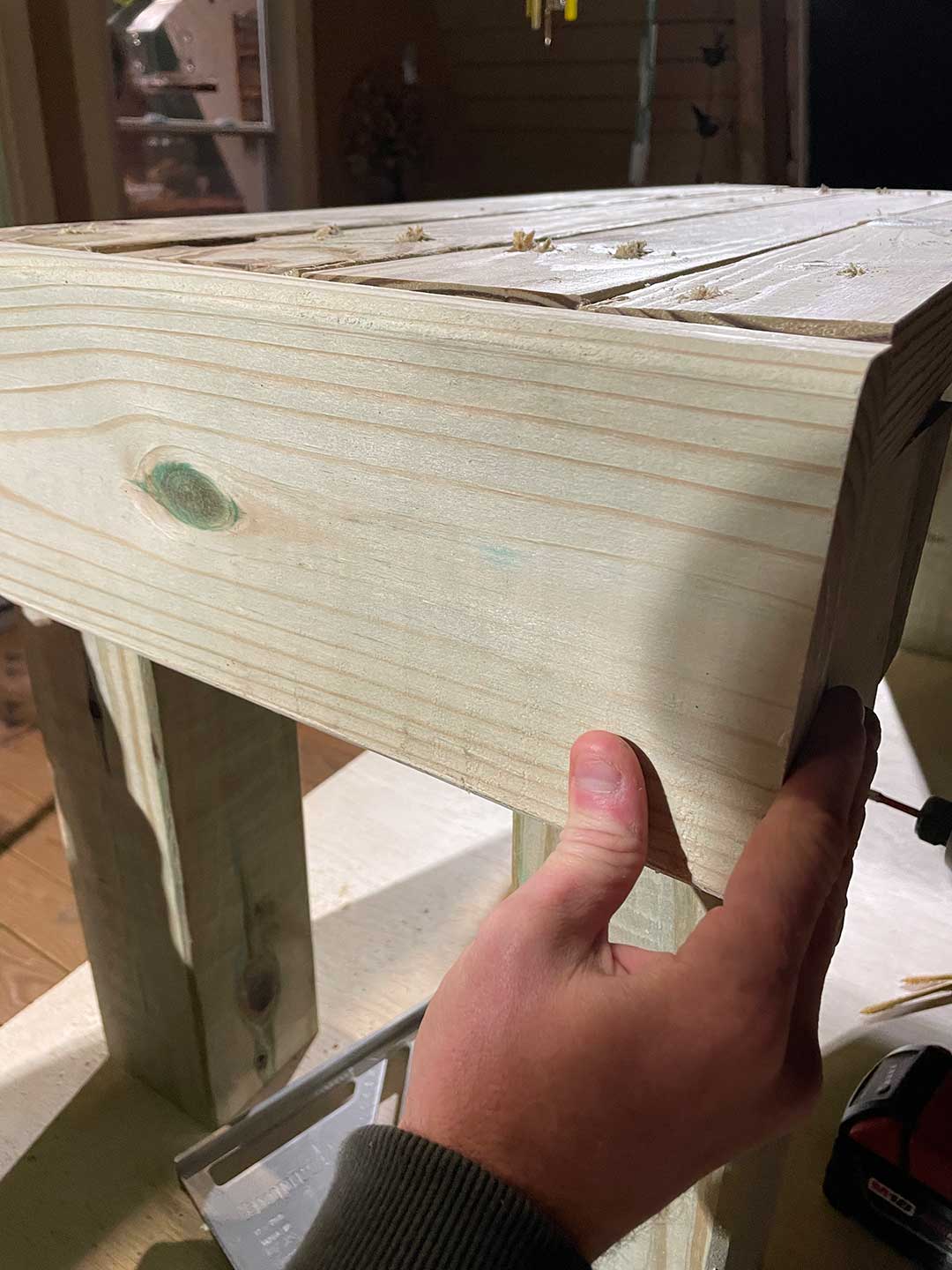 A person holding a piece of wood in place.