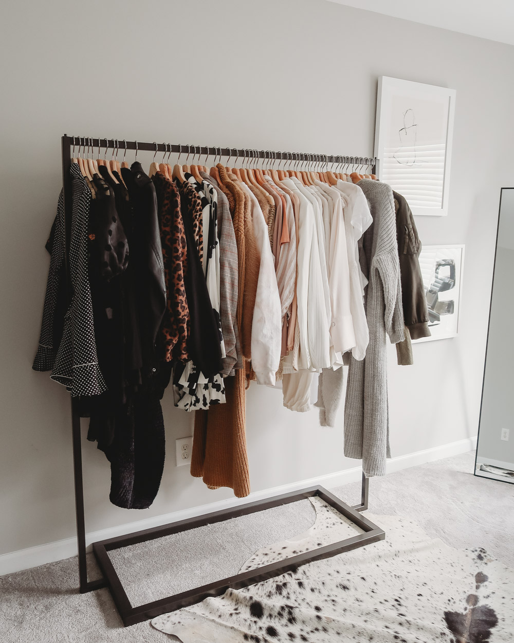 A modern and organized clothing rack sitting against a wall.