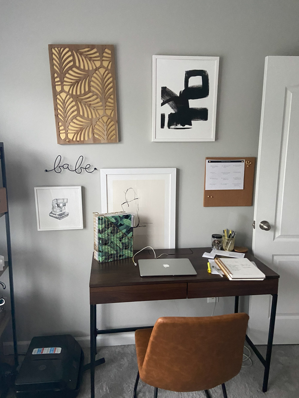 A small desk with artwork on the wall above it.