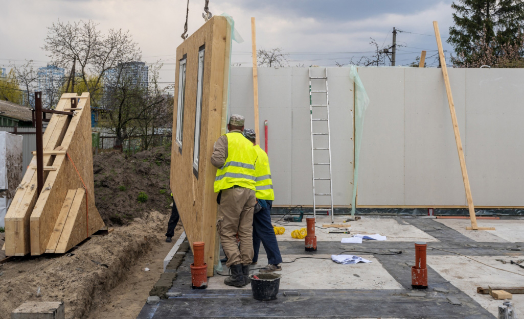Pros attach a wall at a build site. Pros attach a wall at a build site.