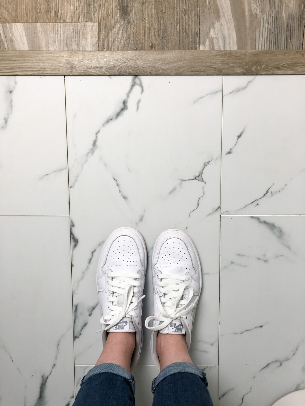 Women’s shoes standing on marble tile flooring with wood trim.