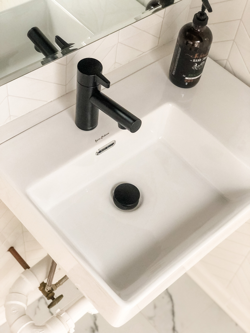 White vessel sink with black touchless faucet.