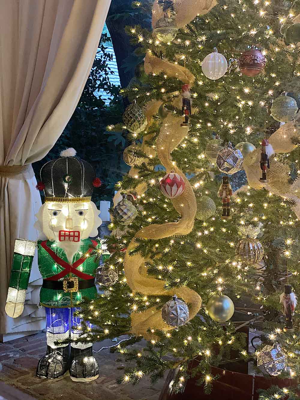 Christmas tree lit in the evening with LED Nutcracker next to it