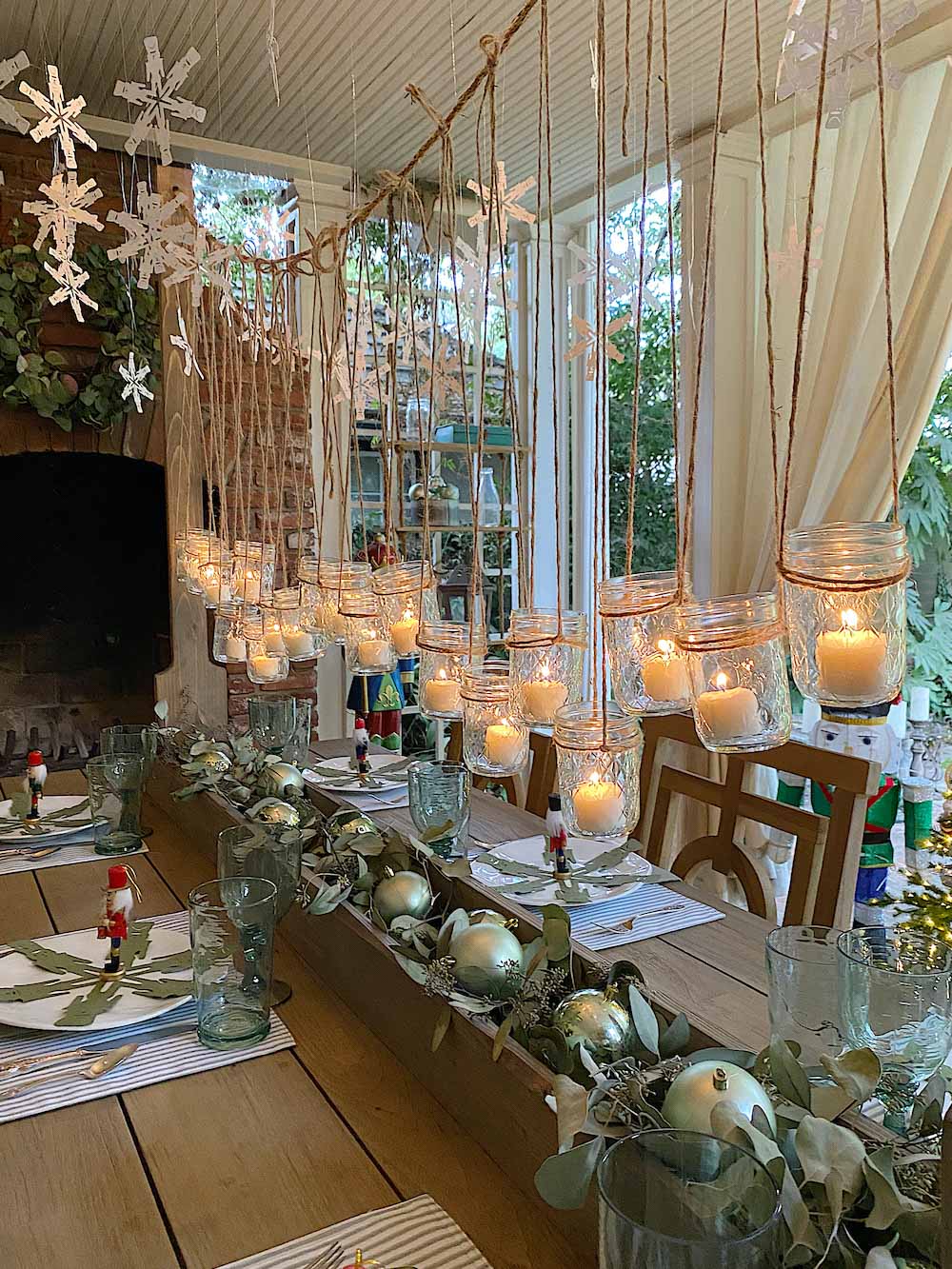 Hanging votive centerpiece over styled holiday dining table with fireplace in background