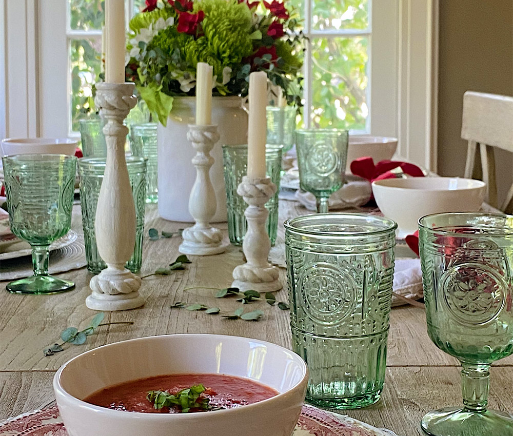 Cups, glasses, and flowers on a dining table spread.