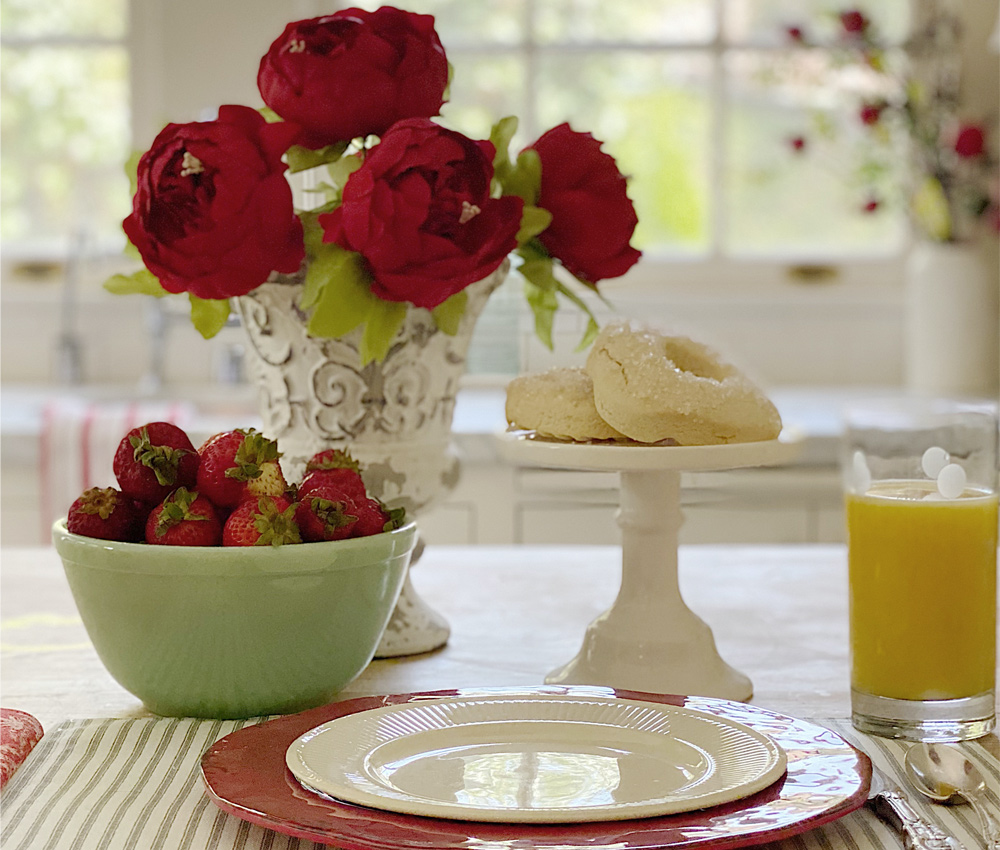 Plates, flowers, and food on a dining table spread.