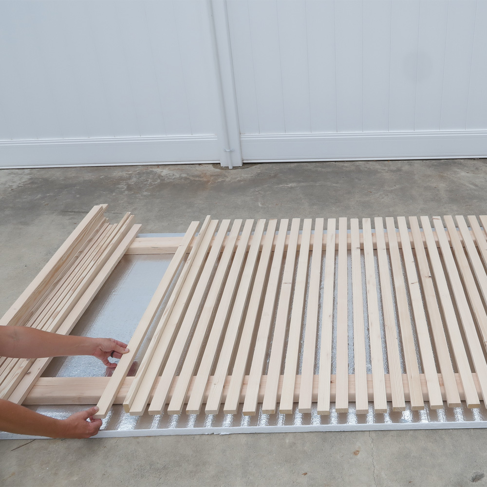  Wood structure on the ground with a person attaching furring strips.