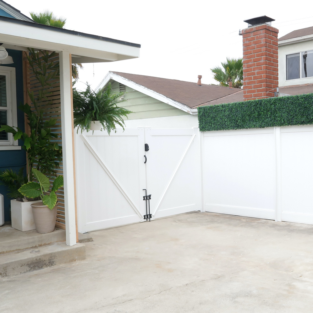 Right angle of completed white privacy fence with faux greenery panels.