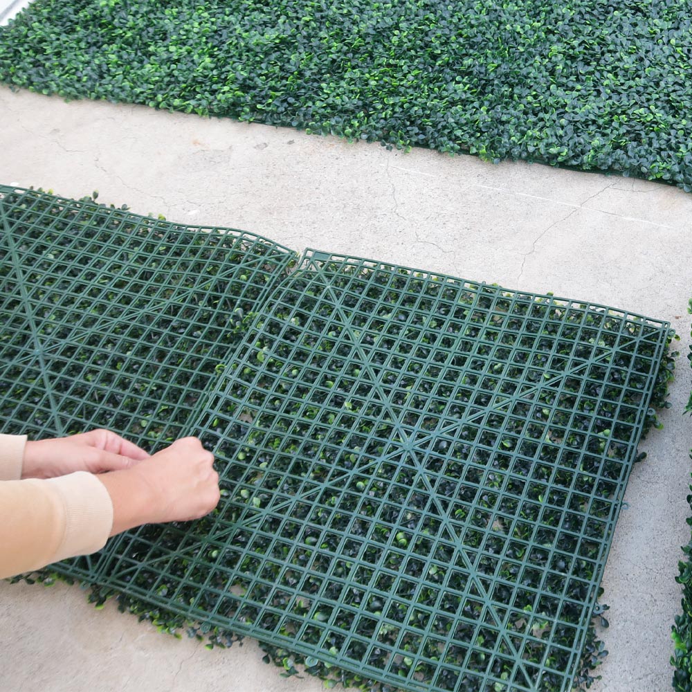 Person connecting two greenery panels together.