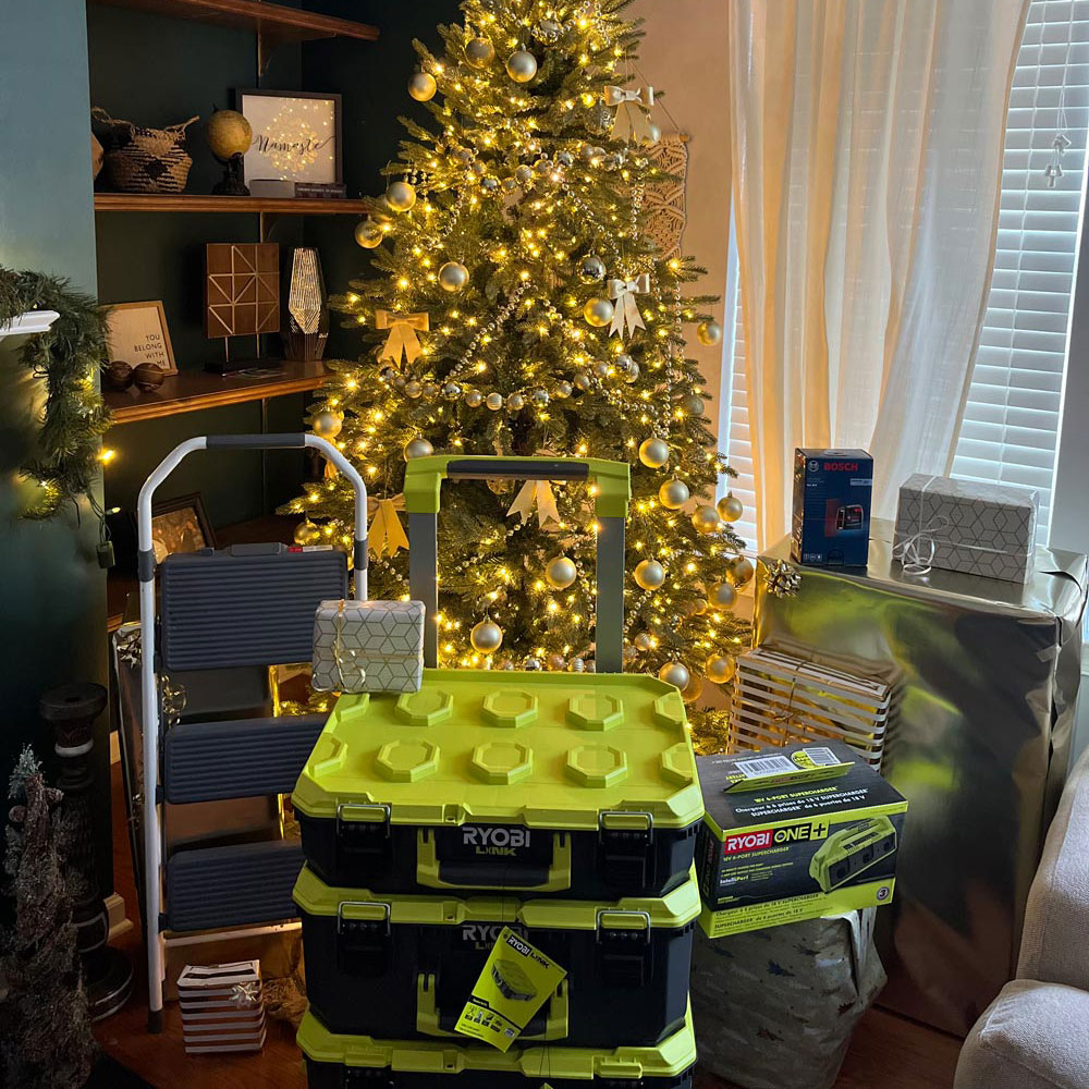 Lit Christmas tree with Ryobi storage unit, ladder, and additional products.