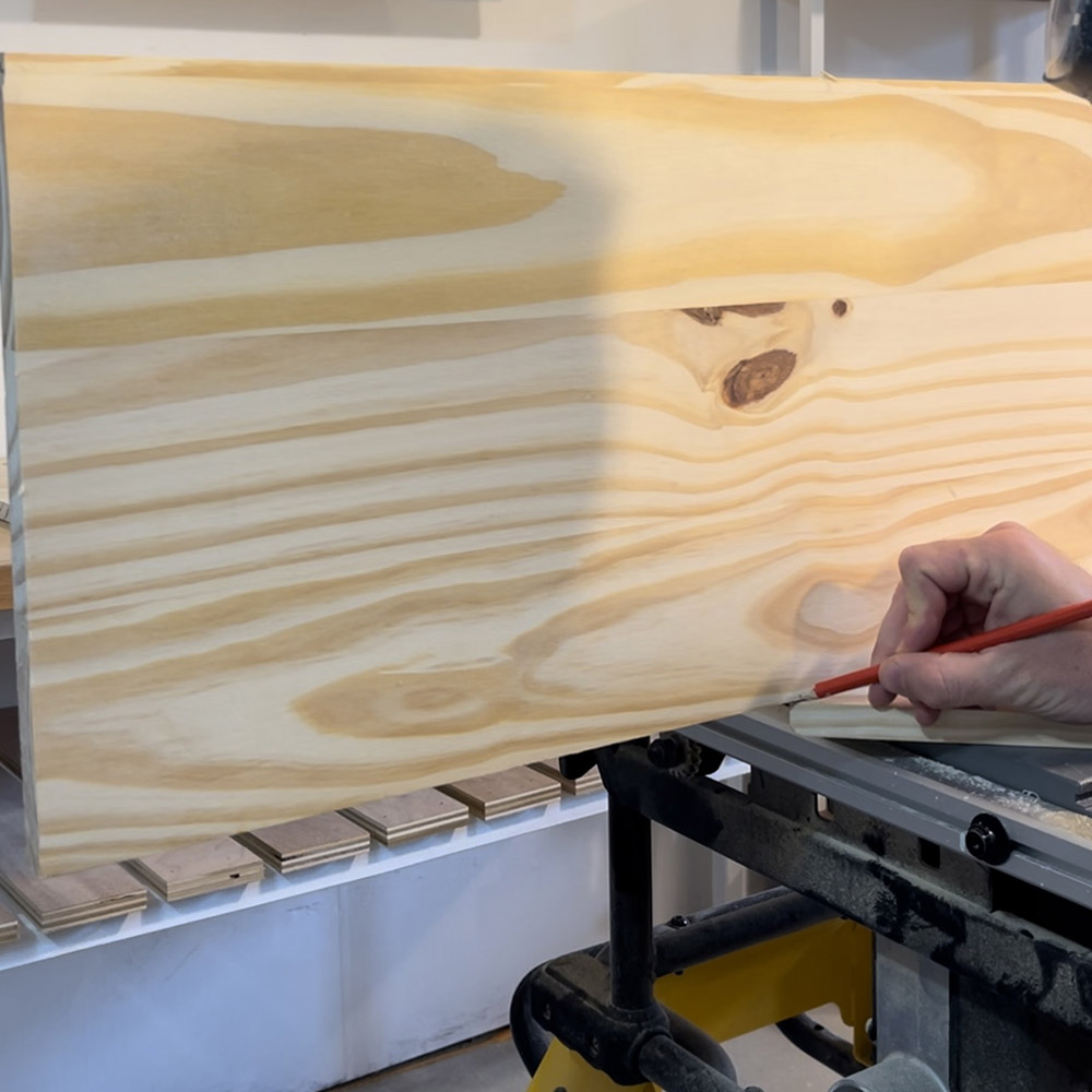 A man marking a point on a piece of wood with a pencil.