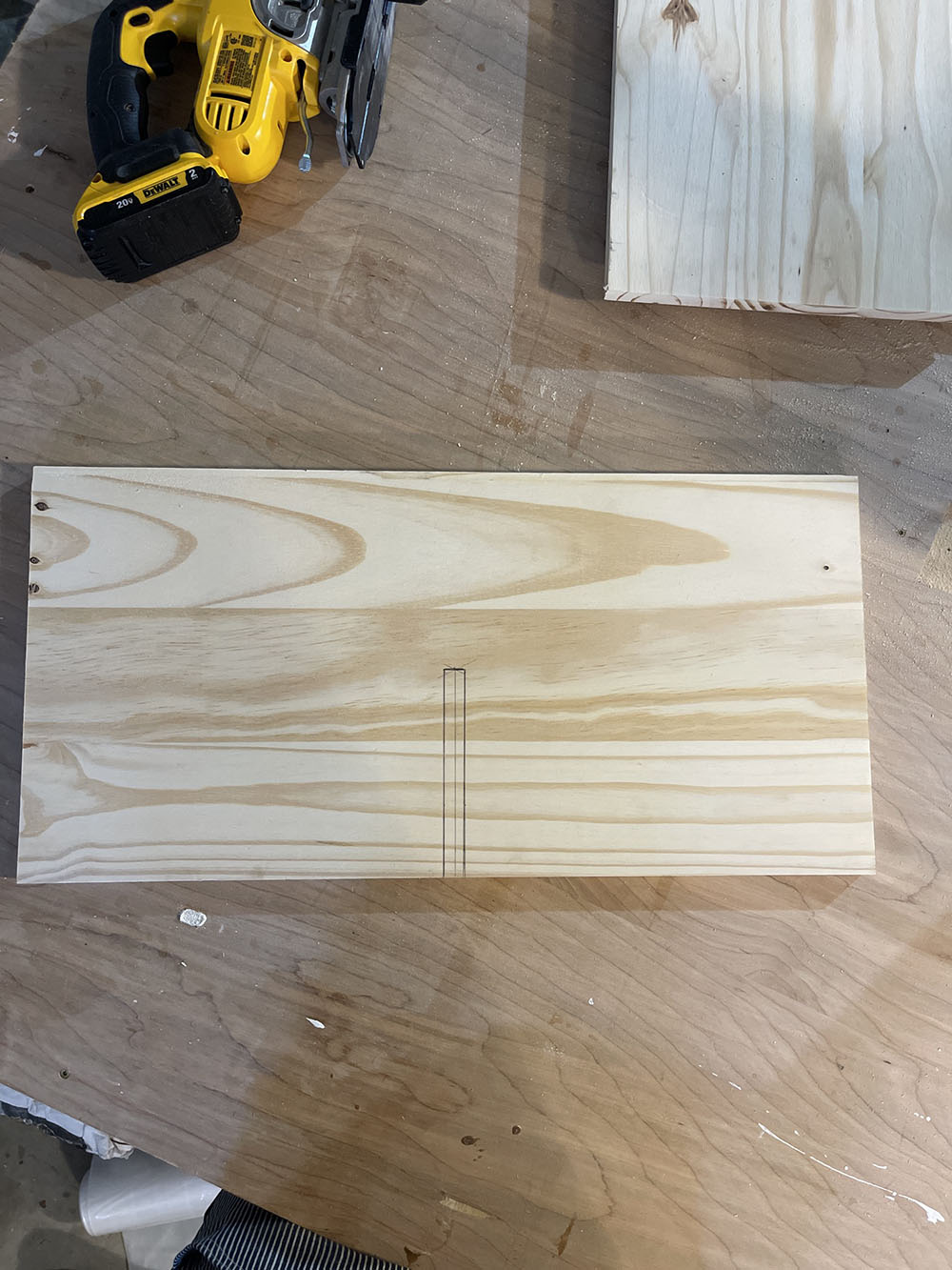 A piece of wood with a small rectangle drawn out of it.