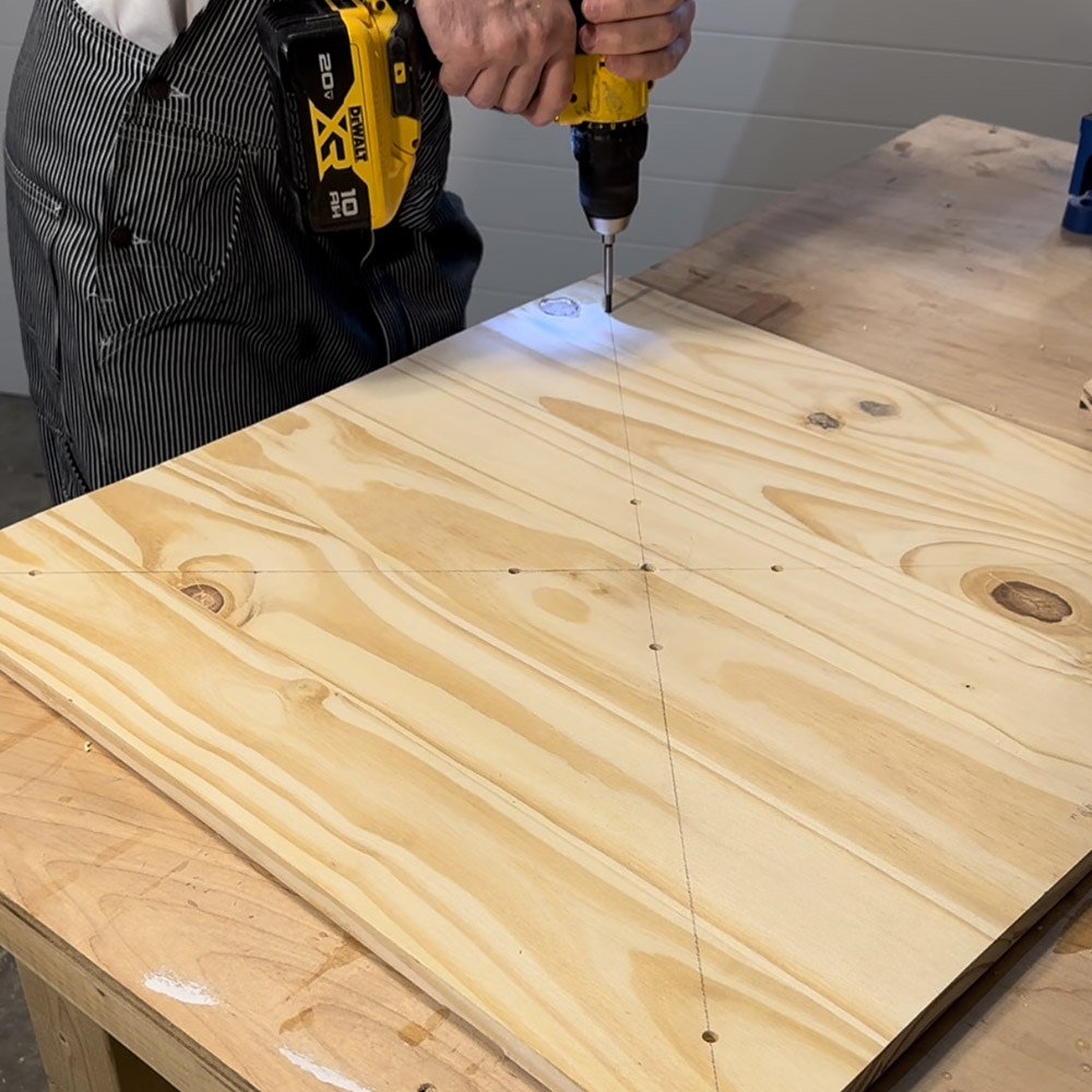 A man drilling holes into a piece of wood.