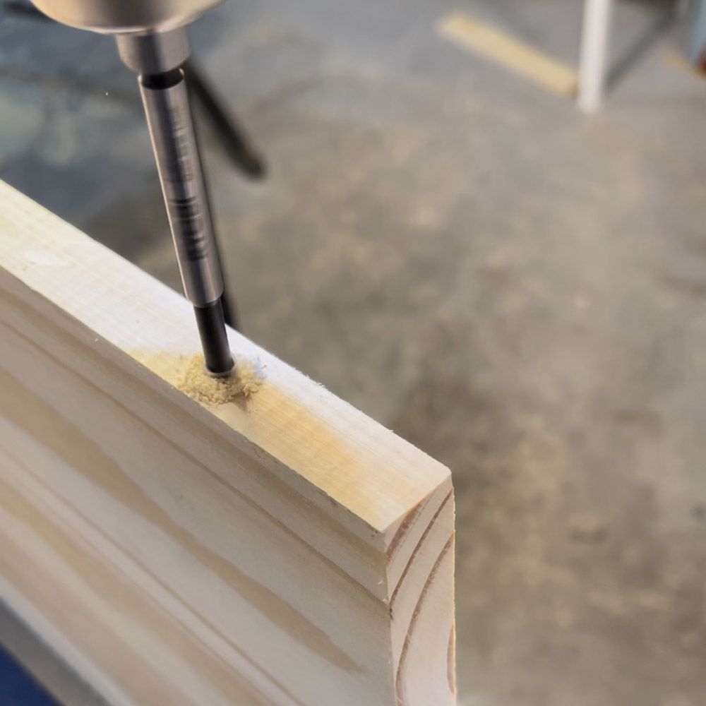 A man drilling into the side of a wooden plank.