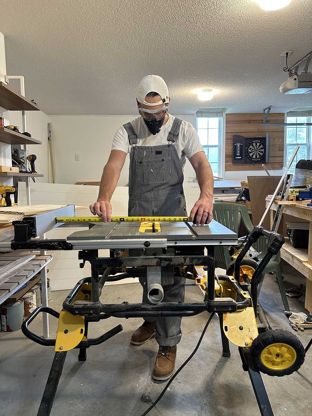 A man measuring a plank of wood on a table saw.