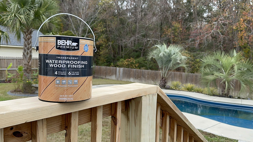 Waterproof wood finish being applied to the railing of a deck.