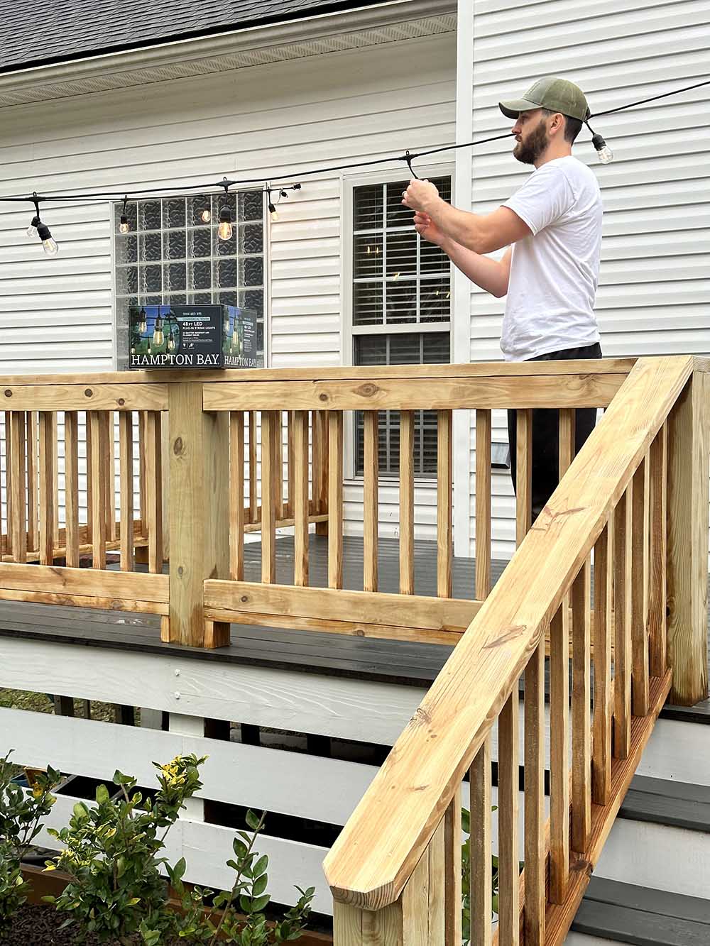 A man hanging up outdoor lights.