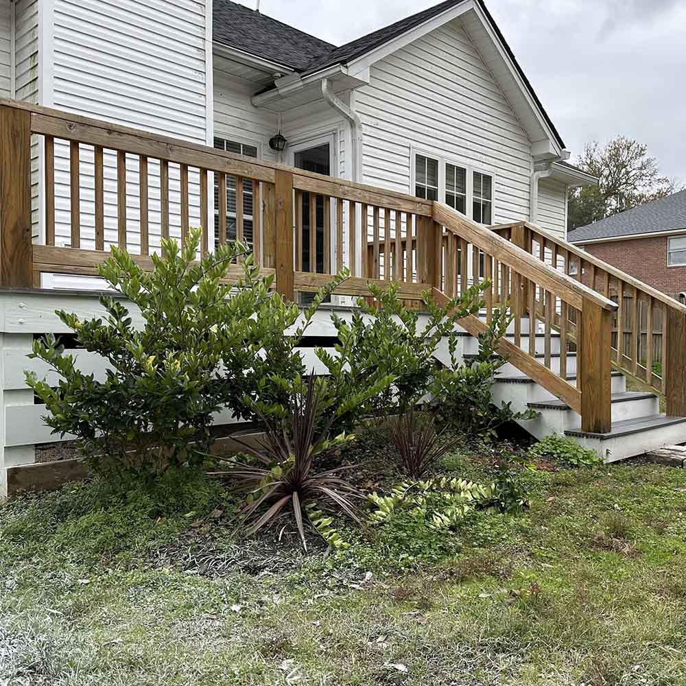 A side shot of bushes surrounding an outdoor deck.