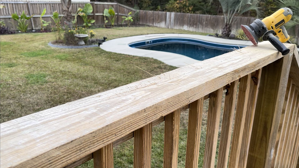 A sander resting on a wooden patio rail.