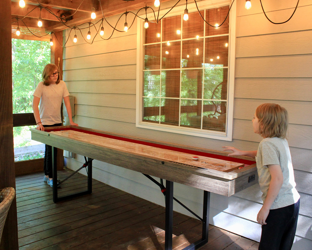 Two children playing on a shuffleboard table. Two children playing on a shuffleboard table.