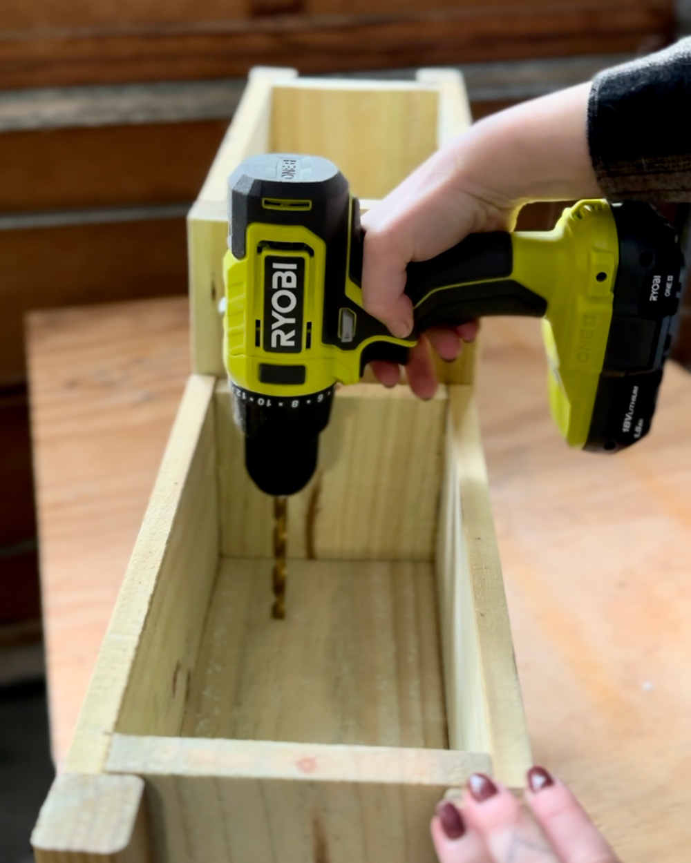 A person using a Ryobi drill to make drainage holes. A person using a Ryobi drill to make drainage holes.